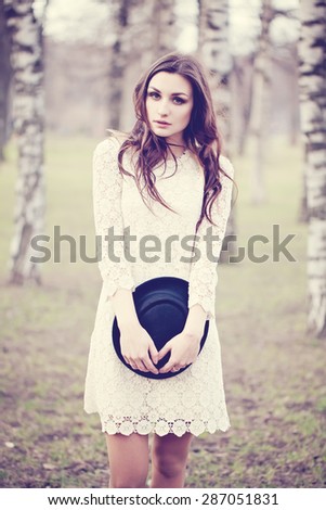 Girl Fashion Model in Park. Makeup, Windy Curly Hair, White Retro Dress, Hipster hat