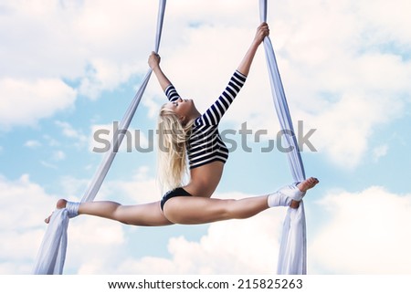 Young woman gymnast. On sky background.
