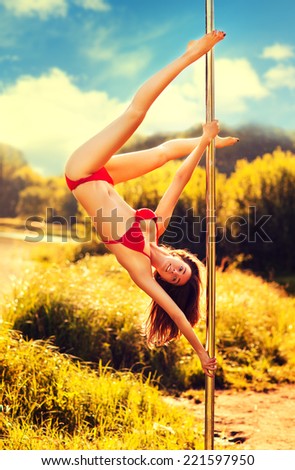 Young slim pole dance woman on nature background.