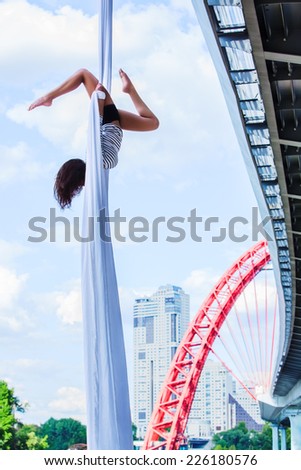 Young woman gymnast. On city and sky background.
