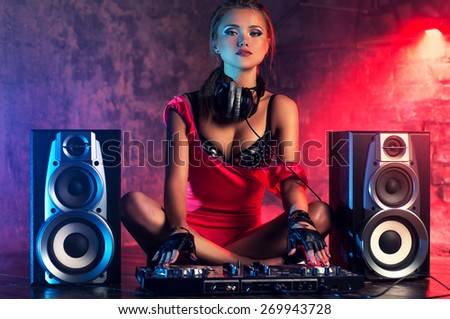 Young sexy woman dj playing music. Big loud speakers, headphones and dj mixer on floor.