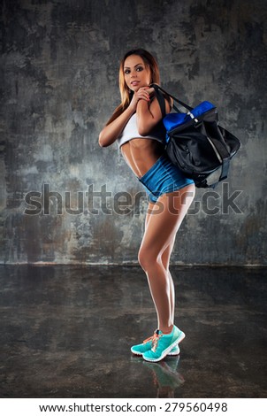 Young slim sports woman standing with big bag on shoulder.