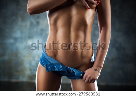 Young sports sexy woman abdominal muscles. Woman covering by hand naked breast.