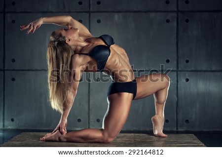 Strong woman bodybuilder on wall background.