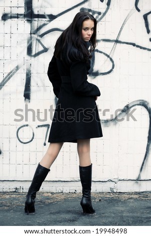 Slim woman turning back on graffiti wall background.