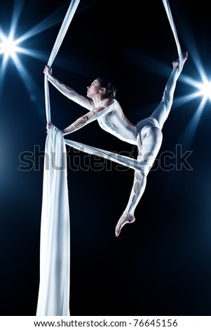 Young woman gymnast. On black background with flash effect.