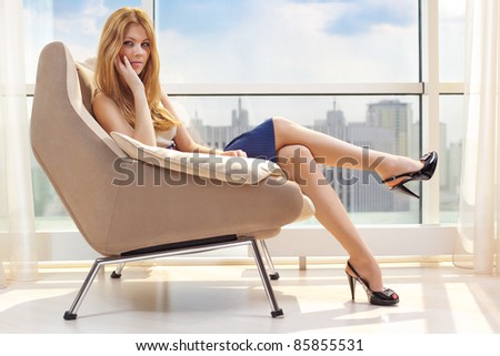 Young woman sitting on chair on window background.