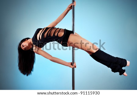 Young pole dance woman. On blue wall background.