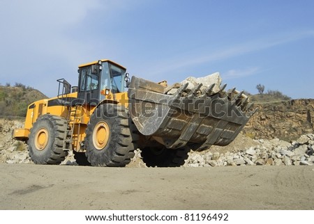 Front loader machine scooping up granite stones in a quarry