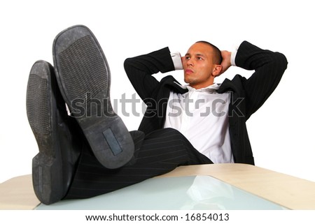 Relaxed Businessman In Office A young satisfied businessman sitting by desk at office feet on table thinking. Isolated over white.