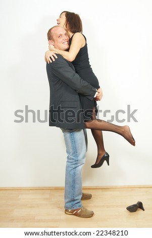 A young man lifts his cute girlfriend. They are in love and very happy.
