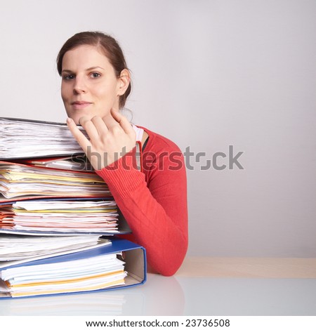 A young woman in front of a stack of paperwork. A lot of copyspace.