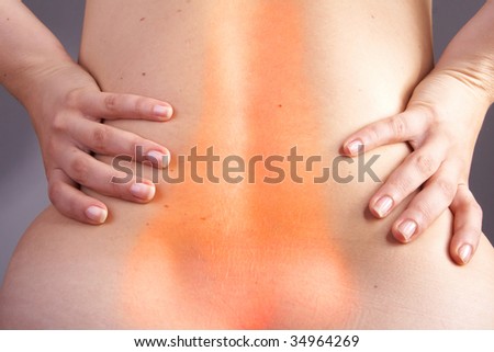 Young woman with sever back pain. She is holding her lower back. Over white background. The hurting area was saturated in red to symbolize the pain.