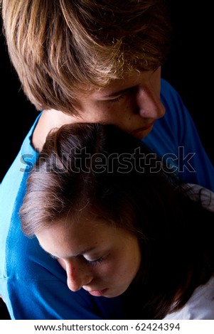 Young couple hugging each other in love over black background.