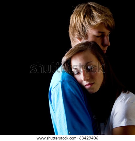 Young couple hugging each other in love over black background.