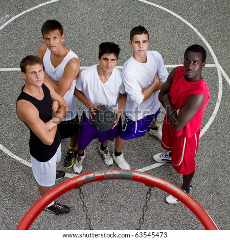 Young group of guys under a basketball hoop with stylish street clothes.