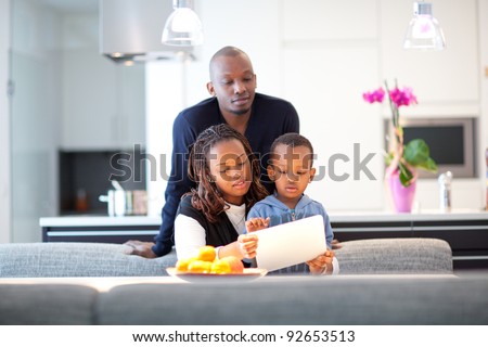 Kitchen setting with young black family playing with a tablet pc.