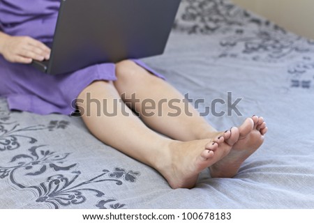 Legs and feet of young lady working on laptop