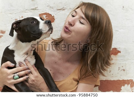 Young lady blowing air into face of Pit Bull puppy