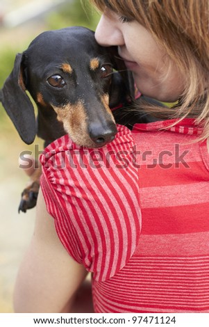 Dachshund dog looking over shoulder while owner gives a loving hug