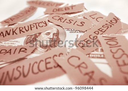 Business concept image. Dollar bank-note laying with peaces of paper with inscriptions. Bankruptcy, crisis, regression, failure in business concept. Focus on franklin eyes. Red colored image.