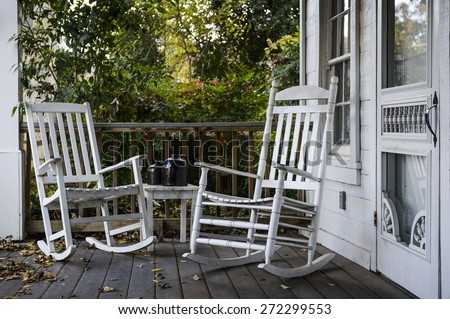 two old rocking chairs on the front porch of an old house