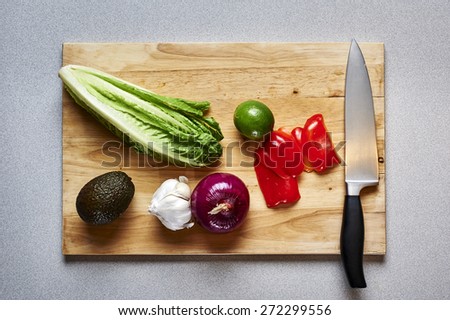 overhead view of a cutting board with vegetables and a knife