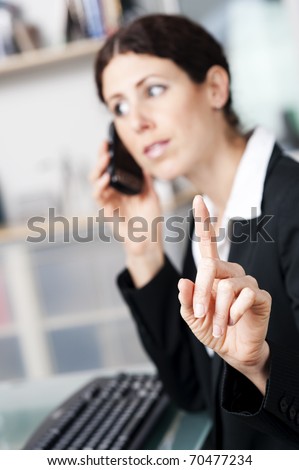 Businesswoman on the phone signaling to someone to hold on.