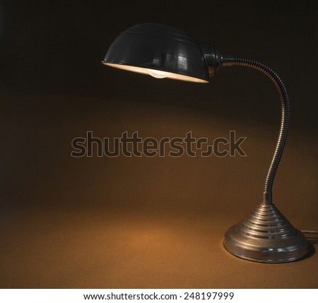Old flexible desktop lamp of aluminum with the light on