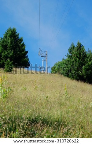 looking up at a ski lift track with wire towers on a grassy mountain side during the summer