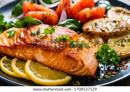 Fried salmon steak with potatoes and vegetables on wooden table Сток-фото © 