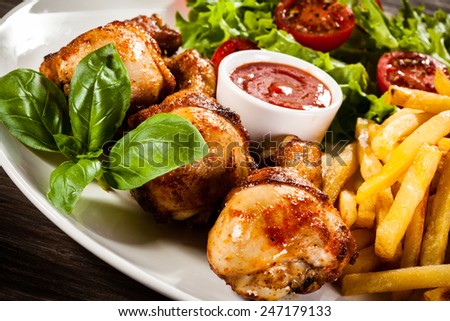 Grilled chicken drumsticks with chips and vegetables