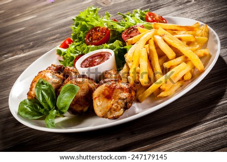Grilled chicken drumsticks with chips and vegetables