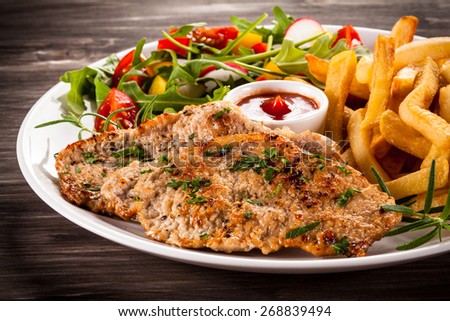 Fried steaks, French fries and vegetables
