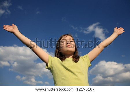 Girl holding arms up in praise against blue sky