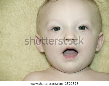 A very cute little infant laying on a fleece, mouth wide open