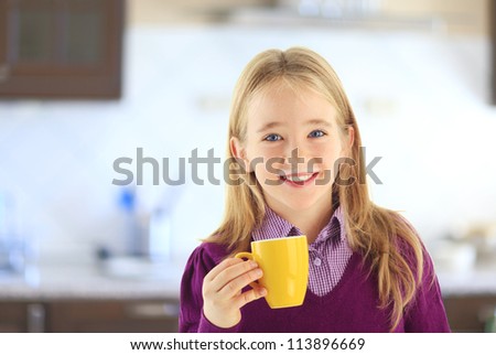 Little girl drinking milk in the kitchen and leaving a mustache of milk on his lip.