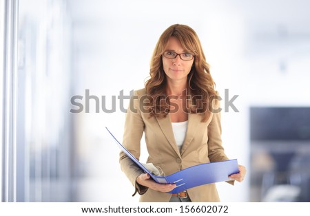 Portrait of smiling blond mature business woman standing in office.