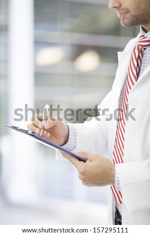 Male doctor filling out medical document.