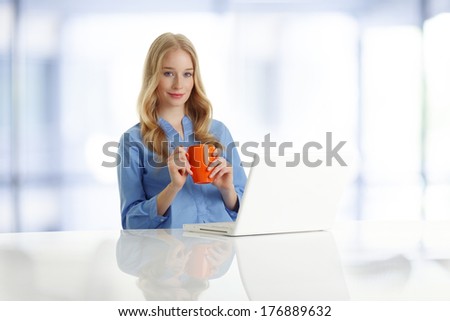 Portrait of beautiful young woman sitting at desk with laptop and mug.