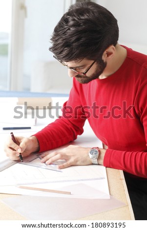 Close-up portrait of small architect studio owner sitting at desk .
