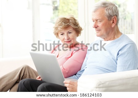 Happy senior couple planning for retirement at home. They surfing on internet with laptop