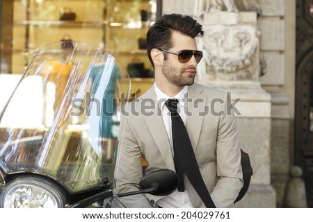 Young modern businessman sitting on scooter.