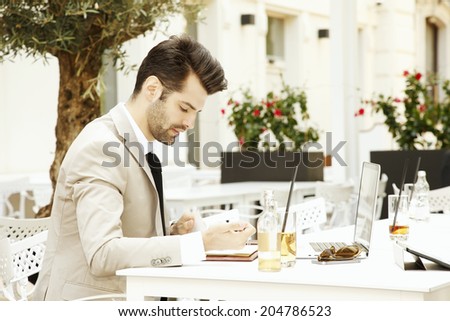 Young businessman sitting in coffee shop while making financial plan. Small business.