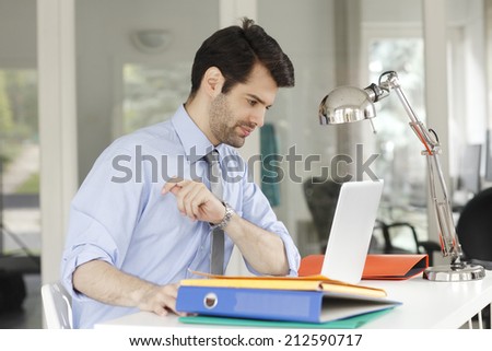 Young businessman sitting at office while working on laptop. Small business.