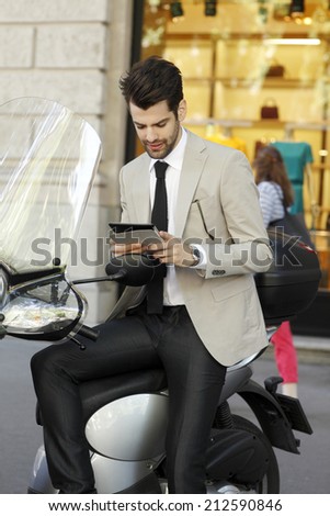 Modern businessman with digital tablet sitting on scooter in the city. Business people.
