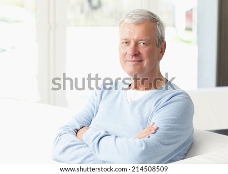 Close-up portrait of active old man sitting at sofa in nursing home.