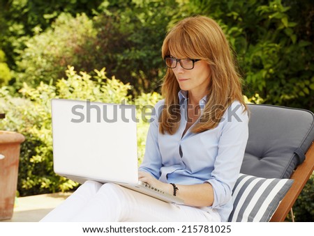 Modern casual woman sitting at garden with laptop, while writing her blog. Business people.