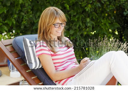 Modern mature business woman fill the form, while sitting in garden at home. Small business.