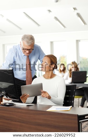 Executive senior business man and businesswoman analyzing data on digital tablet, while sitting at office.
